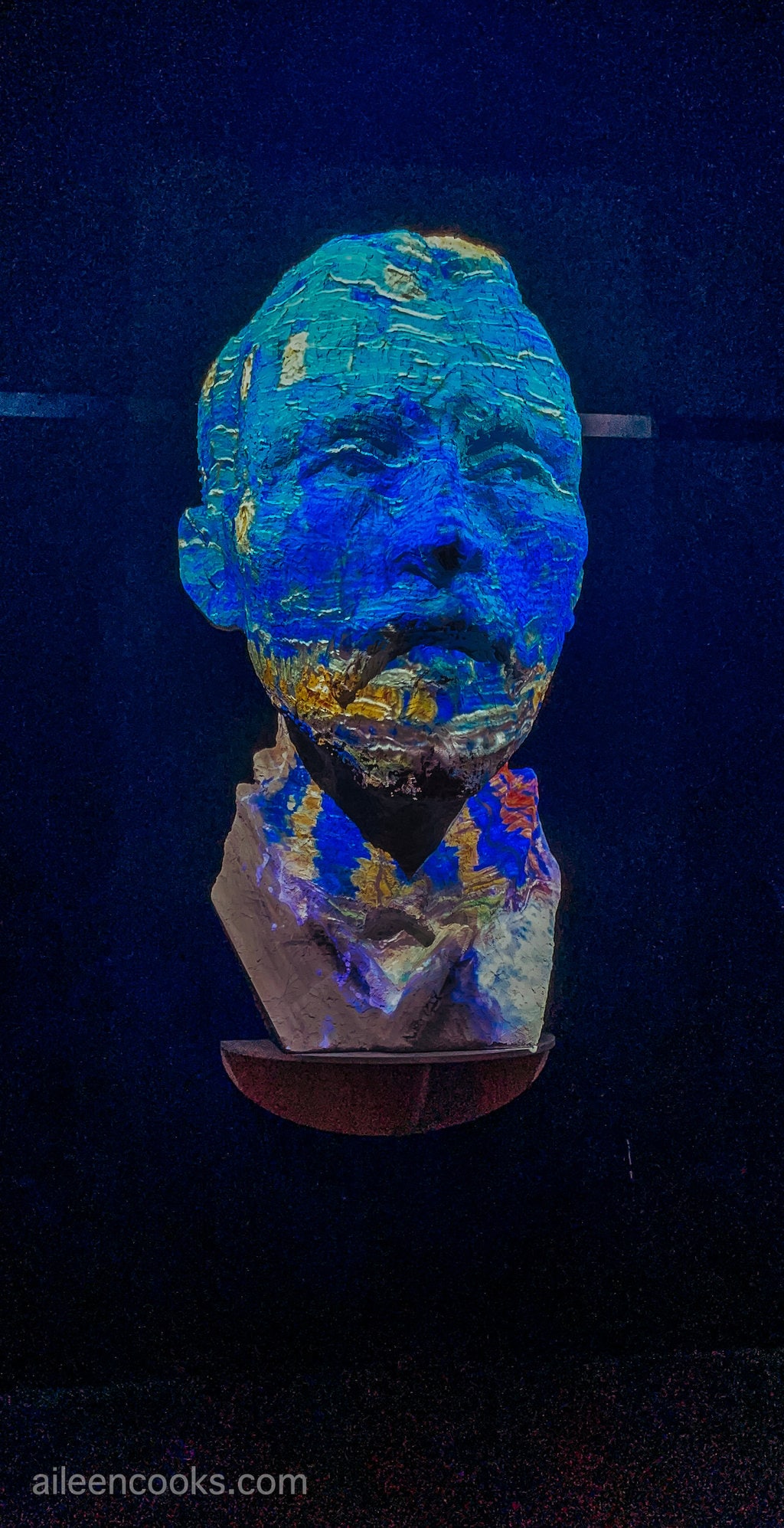 A sculpt of Van Gogh with colors projected on the face.