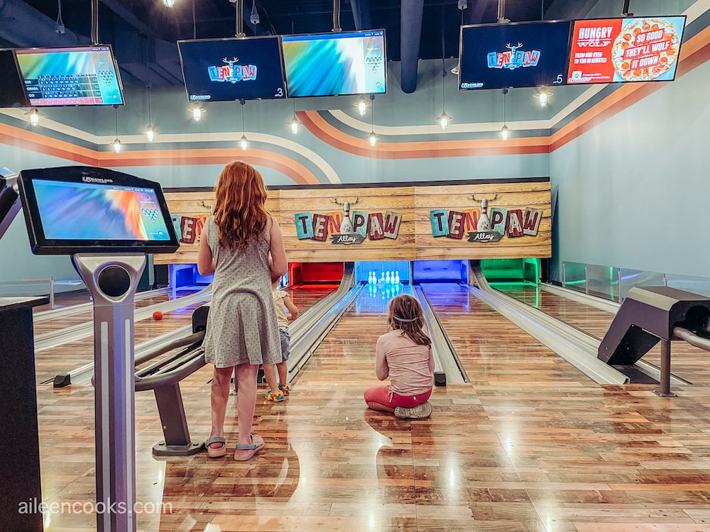 Two girls standing in front of a bowling lane.