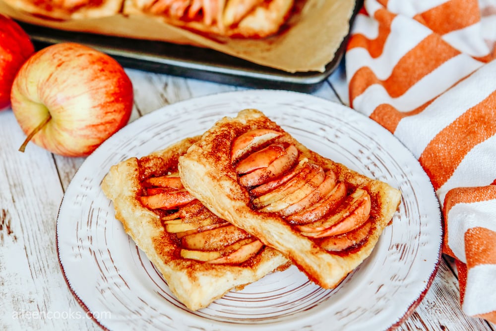 A close up shot of apple tarts, sitting on a white vintage plate.