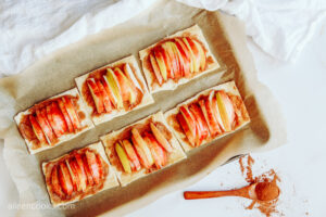 Placing apple slices on puff pastry, with a wooden spoon full of cinnamon beside them
