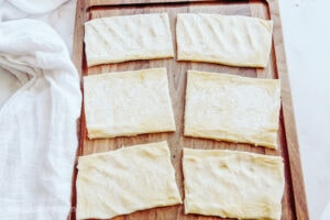 Rectangular pieces of puff pastry on a wooden cutting board