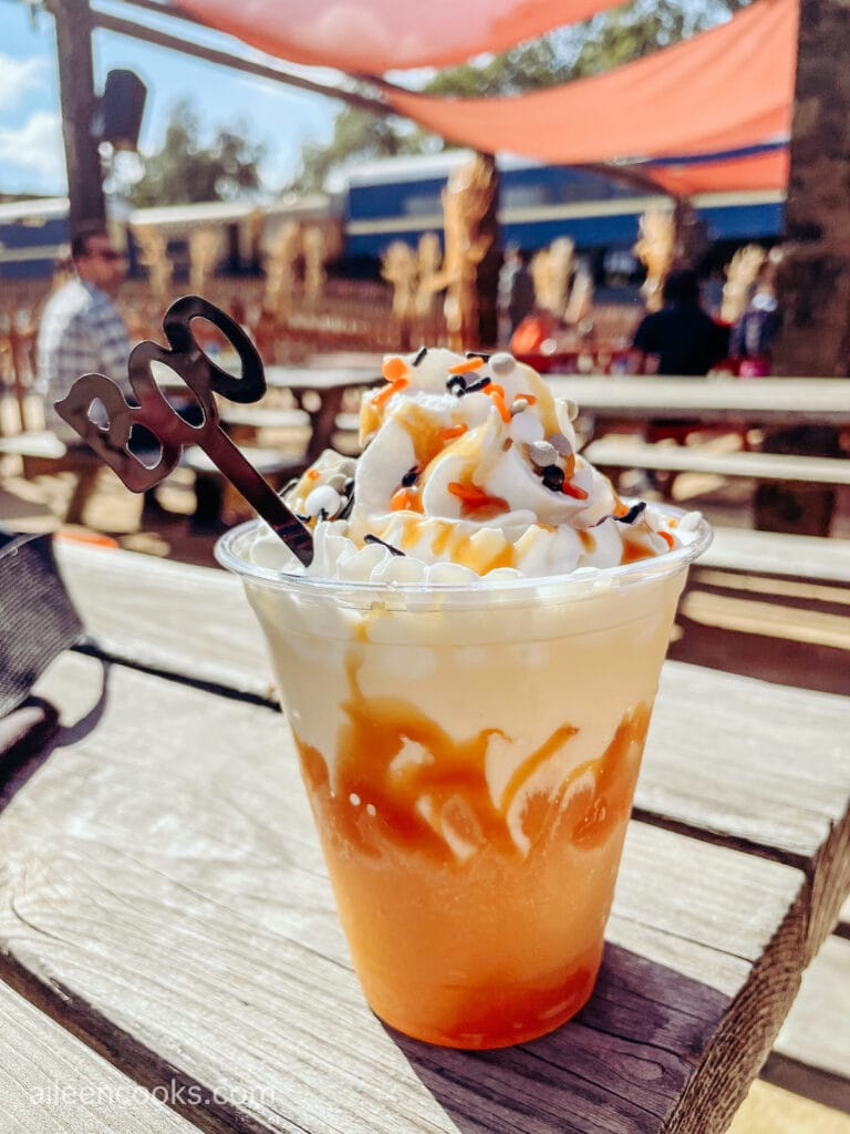 An apple cider float in a clear cup with a straw that says "boo" sticking out the top.