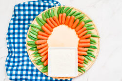 Carrots and snap peas layered on a golden circular tray