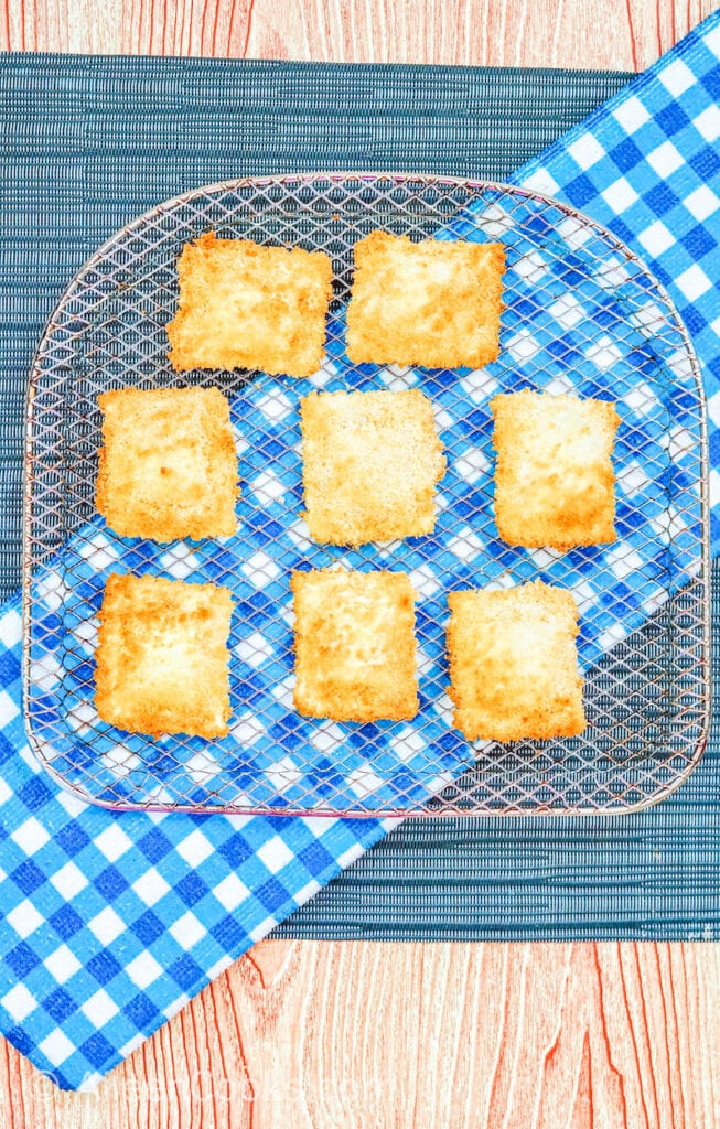 Air fryer ravioli on a cooling rack, sitting on a plaid blue napkin