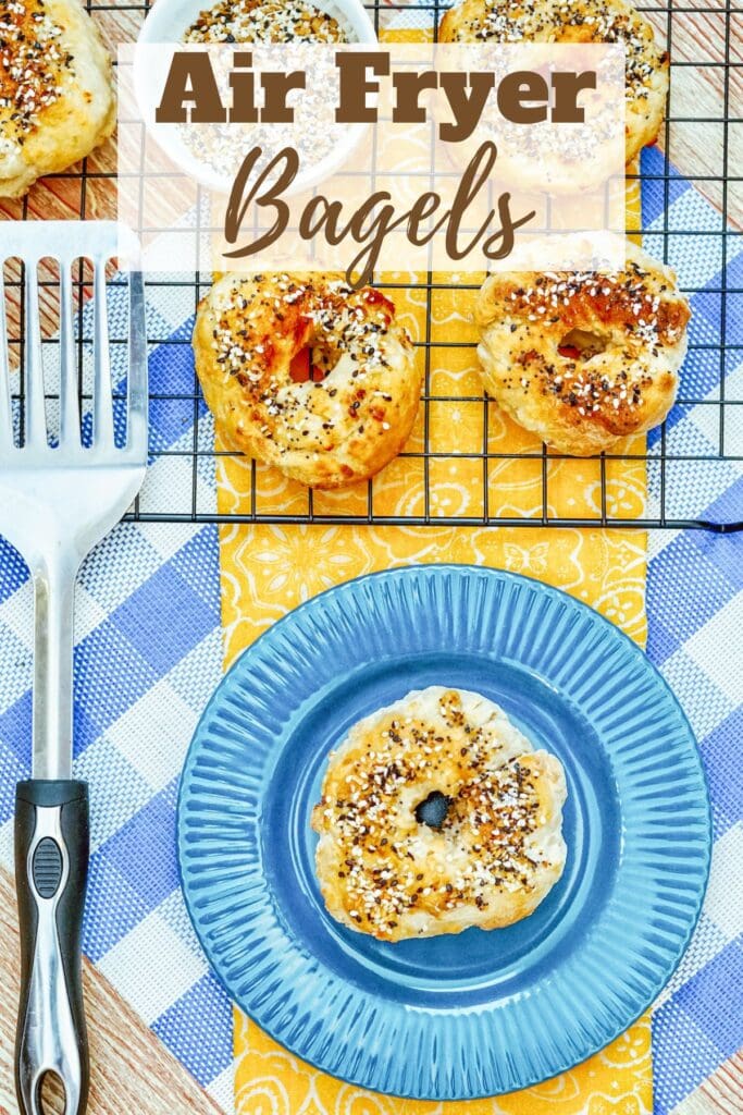 A bagel on a plate below a cooling rack filled with bagels and the words "air fryer bagels" in brown lettering.