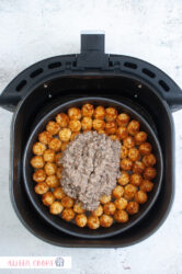 Adding meat sauce to a layer of baked tater tots for a tater tot casserole