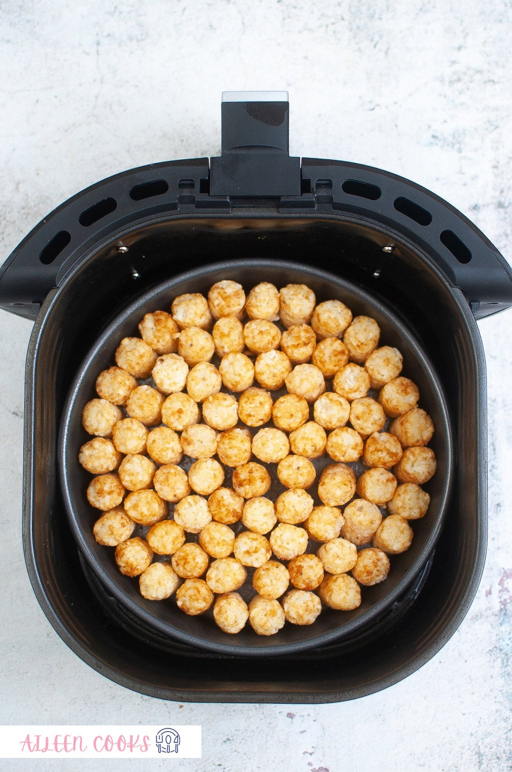 Tater tots layered perfectly in an air fryer basket