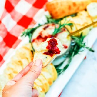 A slice of baguette dipped into homemade cranberry baked brie